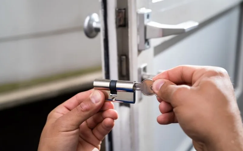 Serrurier insérant un cylindre neuf dans une porte d’entrée