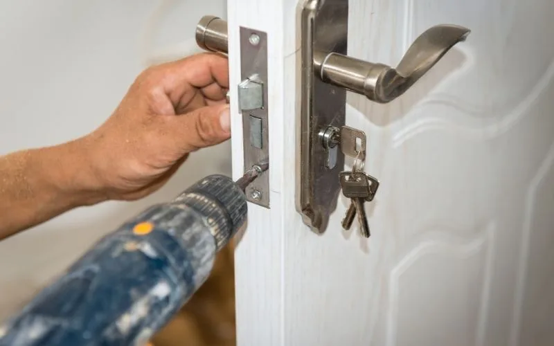 Artisan perçant le chant d’une porte pour poser la serrure