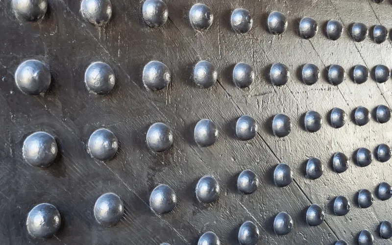 Gros plan sur le parement métallique clouté d’une porte blindée